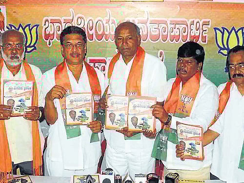 Hassan LS candidate from BJP C H Vijayashankar releases the BJP manifesto related to the district in Hassan on Monday. Navile Annappa, B R Gurudev, Renukumar and others are seen. DH Photo