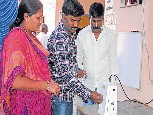Voters take tokens from a newly introduced machine at a model polling station in BBMP health ward office,  Bannerghatta Road. DH Photo