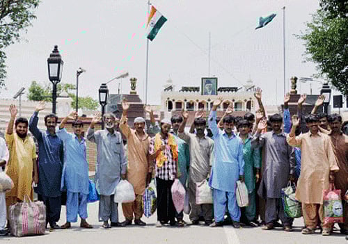 Pakistani prisoners wave at Attari-Wagah land border before their departure for their country on Friday. India had released 37 Pak prisoners including 32 fishermen to Pakistan as a good will gesture. PTI Photo
