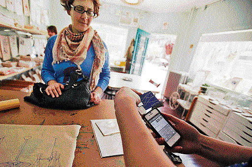 A file photo of a merchant using Square, a mobile payments system, to swipe a customer's credit card. INYT