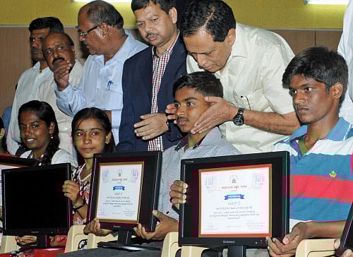Primary and Secondary Education Minister Kimmane Ratnakar distributing desktops to SSLC toppers in an event organized by Karnataka Secondary Education Examination Board at Shiksakara Sadana in Bangalore on Friday. DH photo