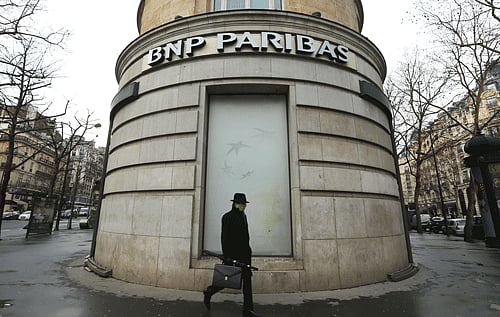 In this Feb. 5, 2013 file photo, a man walks past the French bank BNP Paribas headquarters in Paris. France's largest bank BNP Paribas will pay a record USD 8.97 billion in penalties to settle charges that it ''knowingly and willfully'' processed transactions worth billions of dollars on behalf of Cuban, Sudanese and Iranian entities that had been blacklisted. AP