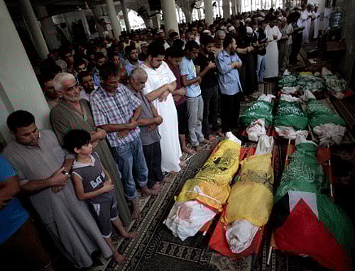 Palestinians mourners pray over the lifeless bodies of nine Palestinians killed in an early morning Israeli missile strike, at Bilal mosque during their funeral in the Khan Younis refugee camp, southern Gaza Strip, Saturday, July 19, 2014. AP photo