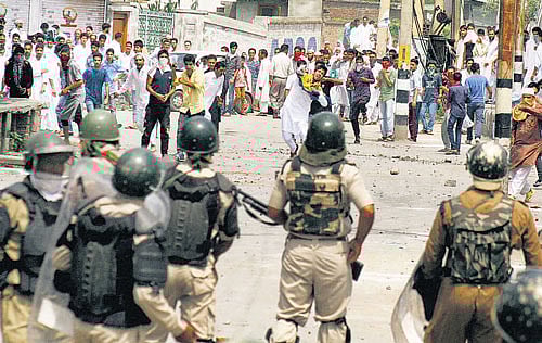 Youth throwing stones at security forces during a clash on Tuesday. PTI