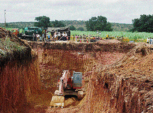 Earthmovers dig a parallel tunnel to rescue Thimmanna, 6, who fell into a borewell three days ago in Sulekeri village of Badami taluk in Bagalkot district, on Tuesday. DH Photo