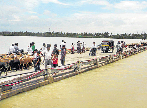 With floodwater receding in the Tungabhadra river, people cross the Kampli-Gangavati bridge at Kampli on Sunday. DH PHOTO