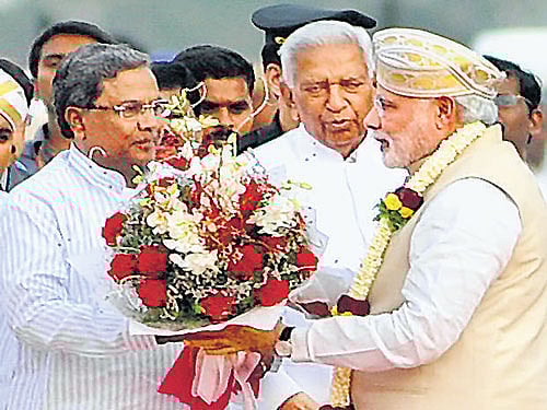 Chief Minister Siddaramaiah welcomes Prime Minister Narendra Modi on his arrival at HAL airport in Bangalore on Tuesday. Modi is on a two-day visit to Karnataka. Also seen is Governor Vajubhai Rudabhai Vala. DH Photo