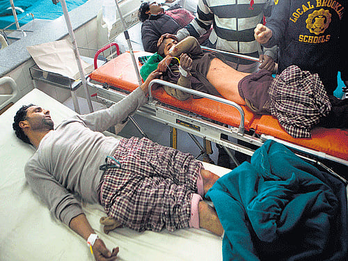 Ghulam Nabi Nayak, left, holds the hand of his eight-year-old son Farooq Ahmad as doctors treat them after they were both injured in a grenade explosion in Srinagar on Saturday. AP