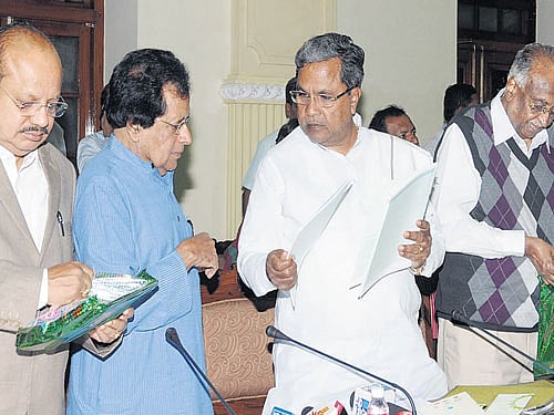 Chief Minister Siddaramaiah hands over a copy of the 'Green Growth Strategy for Karnataka' report to former minister B K Chandrashekar at Vidhana Soudha in Bengaluru on Saturday. Minister T B Jayachandra and Legislative Council Chairperson D H Shankaramurthy are seen. DH PHOTO