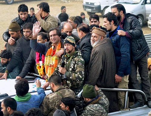 Former Separatist and Chairman of Peoples Conference Sajjad Gani Lone waves as they celebrate his win from Handwara Assembly, in Handwara on Tuesday. PTI Photo(