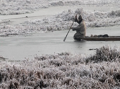 A Kashmiri boat man makes his way through the frozen surface of water of a Lake on a cold and foggy morning AP file photo