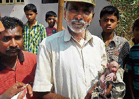 Jagadish, a civic worker, with the baby monkey which he and others in the rescue team helped save. DH Photo