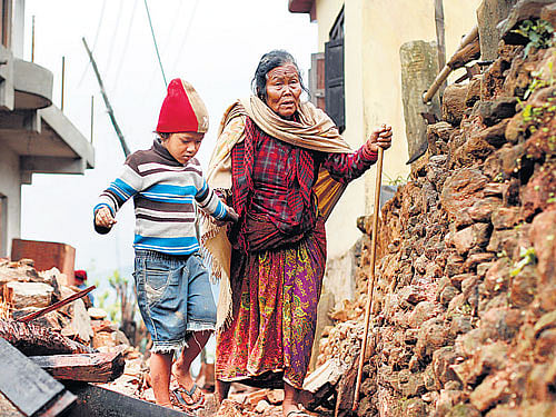 A 79-year-old woman is led through the rubble of collapsed homes by her grandson in Paslang village in Gorkha district. AP