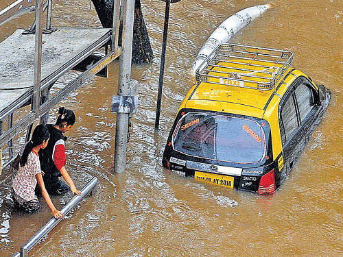 Pedestrians wade through a waterlogged road. DH Photo