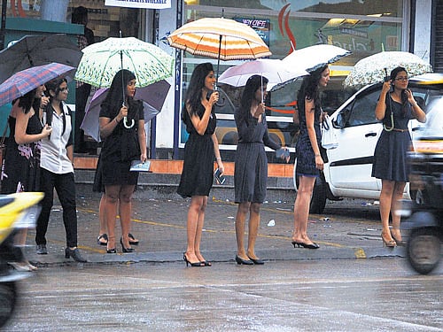 Girls take shelter under umbrellas as showers hit Light House Hill area in Mangaluru on Saturday. DH PHOTO