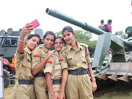 NCC cadets take a selfie in front of an Army tanker at the 'Know Your Army' mela in Bengaluru on Thursday. DH photo