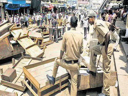 Police keep vigil as Palike workers evict street vendors and shopkeepers from KR Market on Monday. DH photo