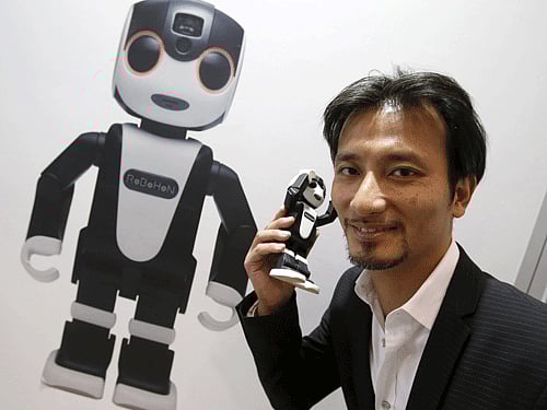 Tomotaka Takahashi (R), CEO of Robo Garage Co and one of the developers of Sharp Corp's RoBoHon, poses for pictures with the humanoid communication robot shaped mobile phone at CEATEC (Combined Exhibition of Advanced Technologies) JAPAN 2015 in Makuhari, Japan, October 6, 2015. Over 500 companies and organisations are exhibiting at CEATEC JAPAN 2015, which will be held until October 10. REUTERS