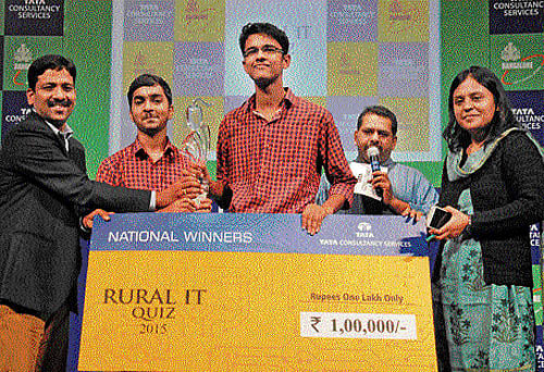 Tata Consultancy Services Bengaluru Centre Head E S Chakravarthy and IT, BT, Science and Technology Department Director Tanusree Deb Burma present a cheque for Rs 1 lakh to the winners of the Rural IT Quiz 2015, Geeve and Karthik Rao, of Little Rock Indian School, Udupi, in Bengaluru on Tuesday. Quizmaster Giri Balasubramaniam is also seen. DH photo