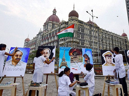 Children paint the portraits of the 26/11 Mumbai terror attack martyrs as a tribute outside Taj Hotel in Mumbai on Wednesday. PTI Photo