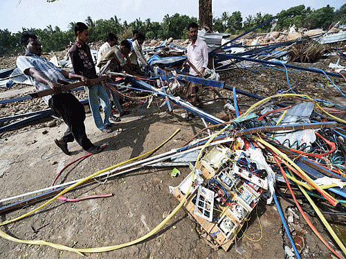 People try to salvage reusable material from their flood damaged Machine on the banks of the Adyar River at Anakaputhur outskirts of Chennai on Monday. PTI Photo.