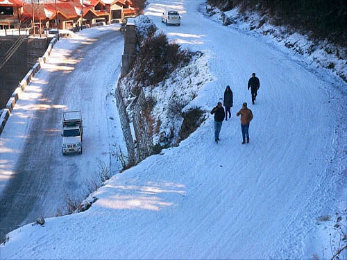 Vehicles move slowly on snow covered road after fresh snowfall at Kufri 17 Kms from Shimla on Friday. PTI photo