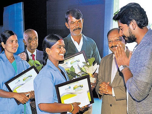 Actor Prajwal Devraj (right) and former Transport commissioner K Amarnarayan present 'Beautiful People-Beautiful Bengaluru' award to pourakarmikas in the City on Monday. DH