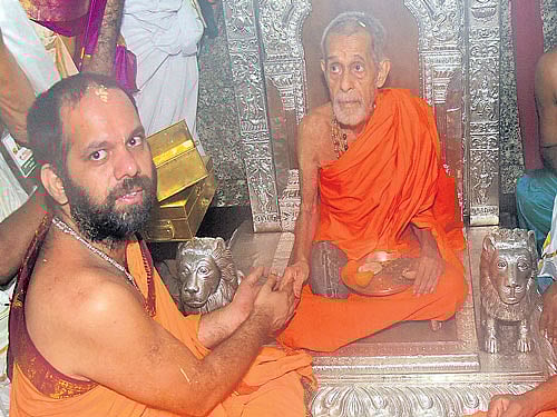 in transition: Pejawar seer Vishweshatheertha Swami ascends the Sarvajna Peetha at the Krishna Mutt in Udupi as part of the Paryaya celebrations in the wee hours of Monday. Outgoing Paryaya seer Vidyavallabhatheertha Swami of Kaniyur Mutt and others look on. DH PHOTO