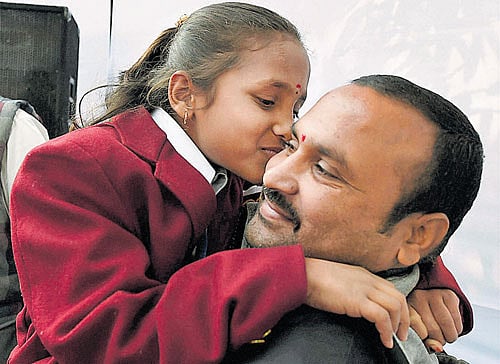 Eight-year old Shivampet Ruchitha of Telangana who will be honoured with National Bravery Award 2015 shares a light moment with her father during a press conference in New Delhi on Monday. PTI
