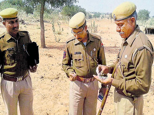Policemen investigate after an unidentified balloon-shaped object picked up by the Indian Air Force's radar was intercepted and shot down over Barmer on Tuesday. PTI