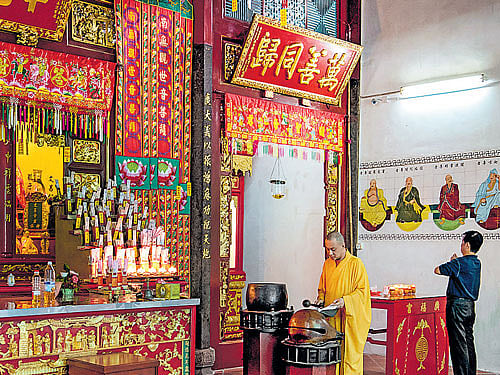 Religion & more A monk strikes a prayer drum in a Chinese temple in George Town.