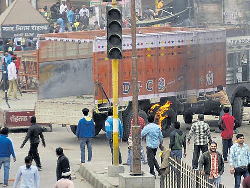 Jat community members torch a truck during their agitation for reservation in Rohtak on Friday. PTI Photo