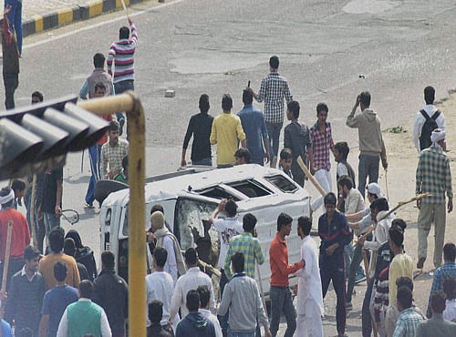 Jat community members smash a vehicle as they turn violent during their agitation for reservation in Rohtak on Friday. PTI Photo