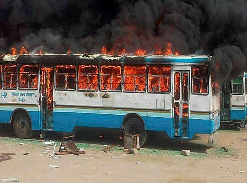 Jat community members torch a Haryana Roadways bus during their agitation for resrvation, in Kaithal on Saturday. PTI Photo