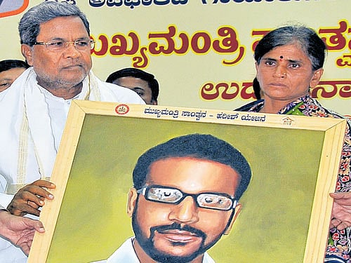Chief Minister Siddaramaiah hands over a portrait of  accident victim Harish to his mother Geetha at the launch of a scheme for accident victims named after him in Bengaluru on Tuesday. DH photo