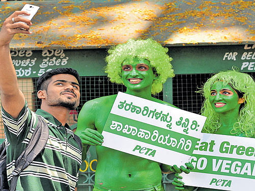 A man clicks a selfie with PETA volunteers who are holding placards to create awareness about veganism in the City on Wednesday. DH photo