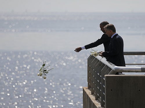U.S. President Barack Obama throws flowers in the River Plate while visiting with Argentina's President Mauricio Macri (R) at the Parque de la Memoria (Remembrance Park) where they honored victims of Argentina's Dirty War, in Buenos Aires