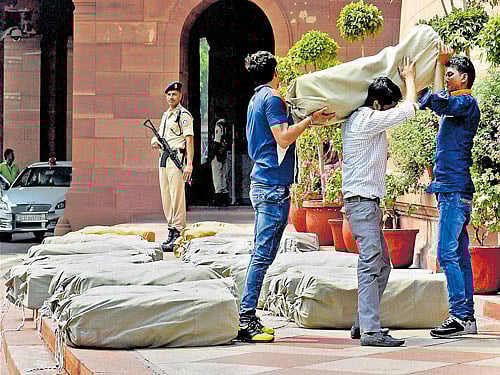 A security person stands guard as workers carry the papers of Uttarakhand Budget for 2016-17 for presentation in the Lok Sabha, in New Delhi on Monday. PTI