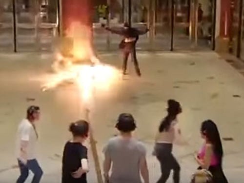 The mock bomber dressed in black walked in and shouted at the crowd at Manchester's Trafford Centre overnight as hundreds of people ran screaming and hid in shops and restaurants. Screen grab.