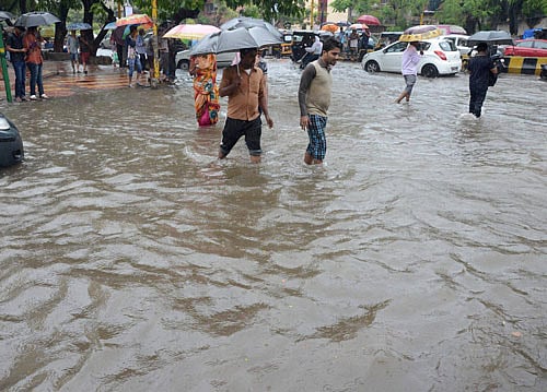 Monsoon effect: People walk through a waterlogged road following heavy downpour in Navi Mumbai. PTI
