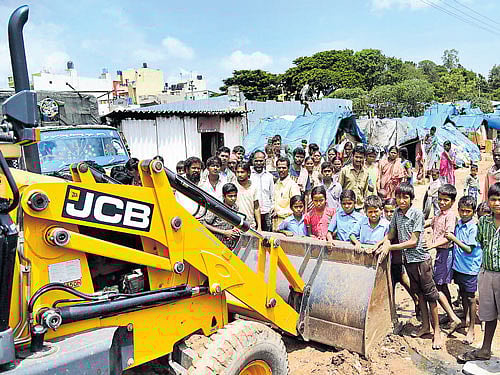 Local residents protest the demolition drive by blocking an earthmover. DH Photo