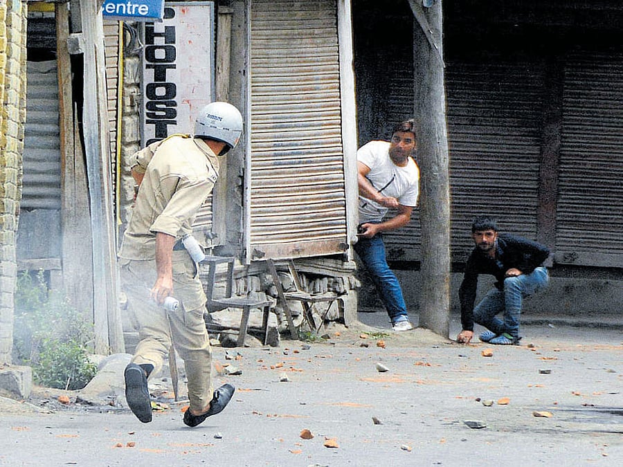 A policeman retaliates during a protest in Srinagar on Saturday. PTI