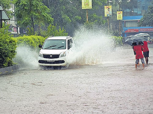 A car navigates on the inundated Green Street Road in Karwar as heavy rain lashed the town on Sunday. DH Photo