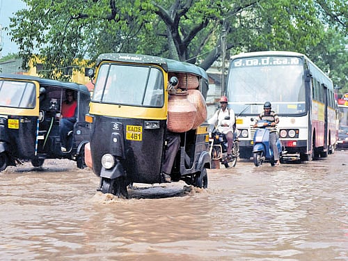 Vehicles wade through the waterlogged road near suburban bus stand in Mysuru. DH Photo.
