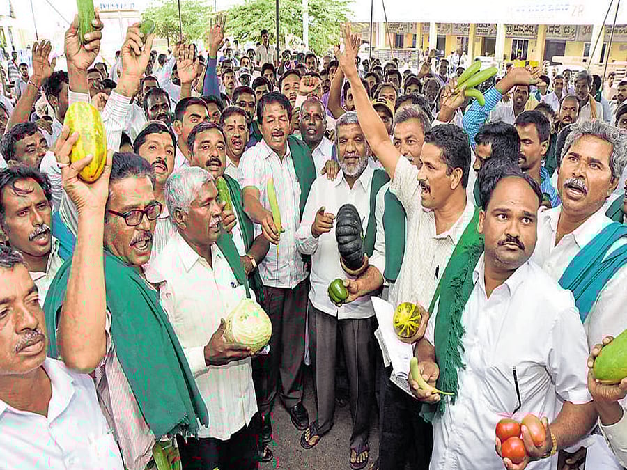 Growers, joined by the members of Karnataka Rajya Raitha Sangha and Hasiru Sene, protest vegetable price crash in Mysuru on Friday. Melkote MLA K S Puttannaiah and others are seen.