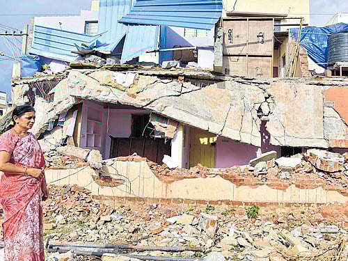 Awomanstands next to ademolished building in Avani Sringeri Nagar onMonday. DH PHOTO