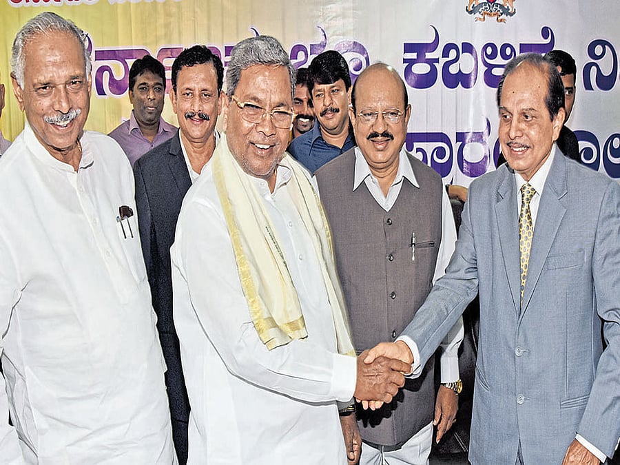 Chief Minister Siddaramaiah greets Justice H H Narayan, the chairman of the special court set up to try government land grab cases at Kandaya Bhavana in Bengaluru on Wednesday. (From left) Revenue Minister Kagodu Thimmappa, Bengaluru Urban Deputy Commissioner  V Shankar and Law Minister T B Jayachandra look on. DH photo
