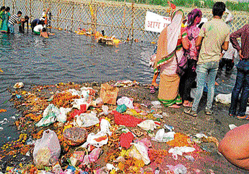 Puja materials like flowers and oil are strewn on the Yamuna Ghat after the immersion of idols of Ganesh on Thursday. DH