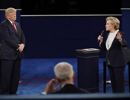 Democratic U.S. presidential nominee Hillary Clinton speaks as Republican U.S. presidential nominee Donald Trump looks on during their presidential town hall debate at Washington University in St. Louis, Missouri, U.S. REUTERS
