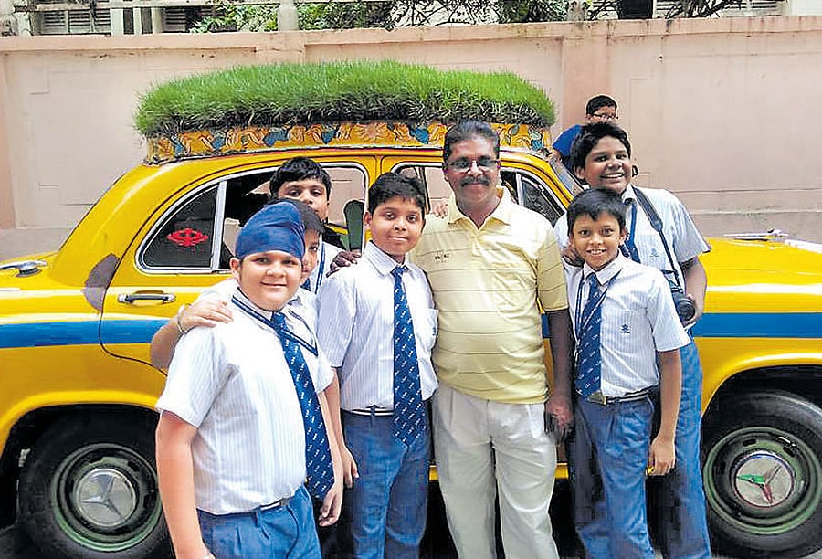 Dhananjoy Chakraborty with students in front of his taxi in Kolkata. Facebook